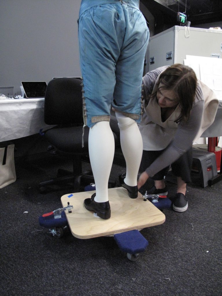 Melinda Kerstein connecting the right leg to an 18th century mannequin 